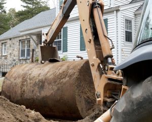 Excavator removing an underground oil tank in front of a home.
