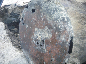 Close-up view of an excavated oil tank with extensive corrosion